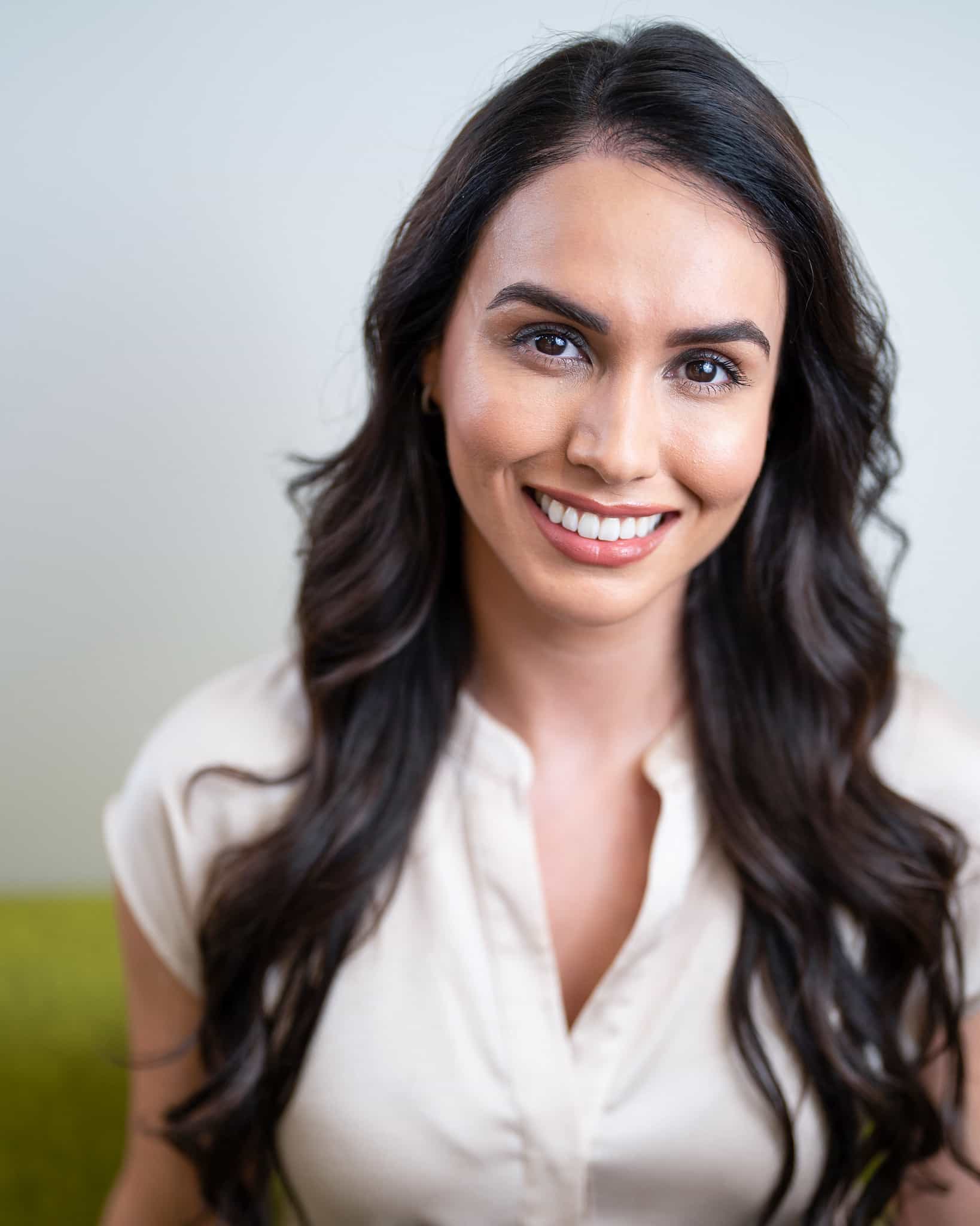 A picture of a woman with a long black hair and wearing a white top looks very happy after receiving the treatment from Dr. Jae Pak