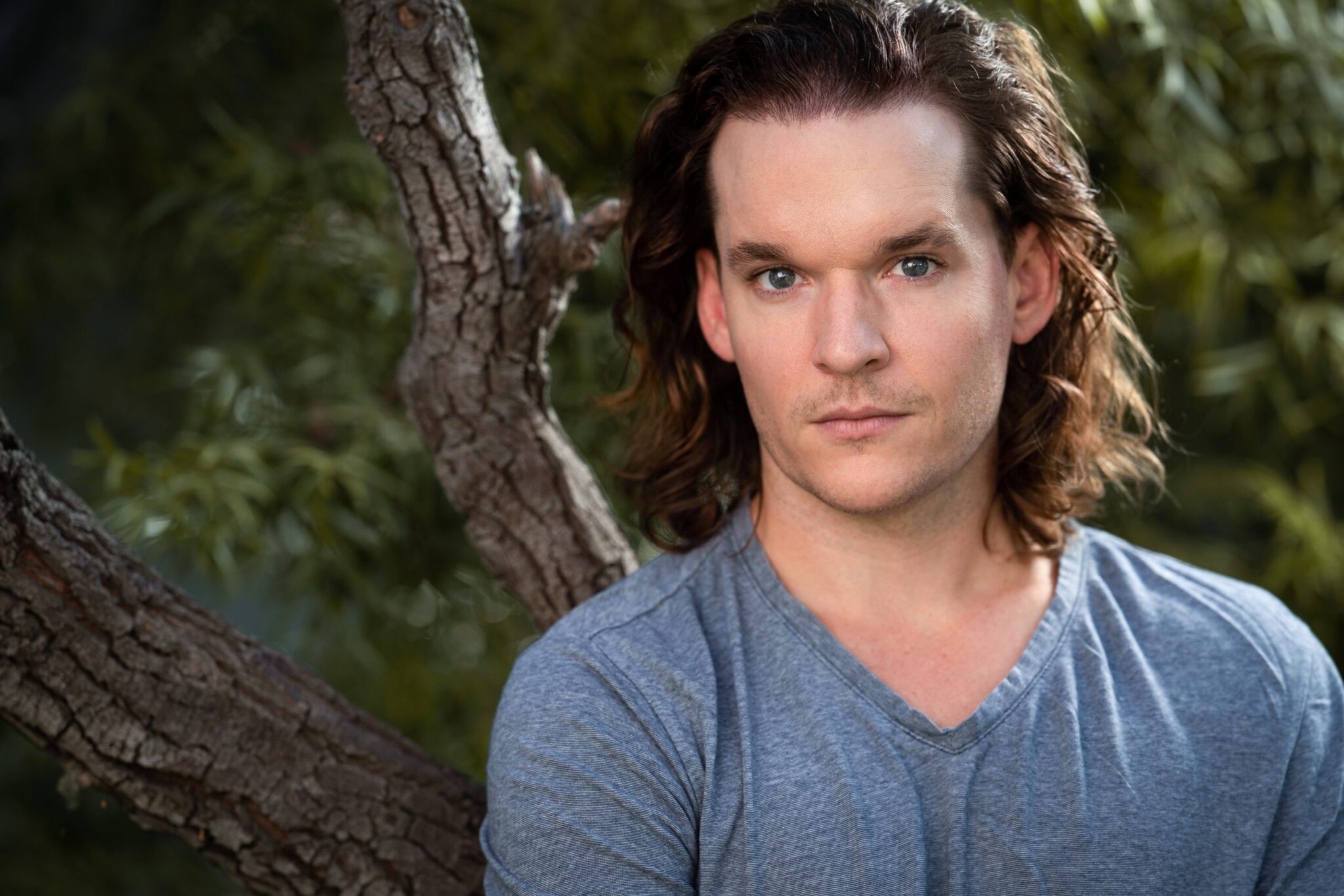 An image of a man standing by a tree with confidence from his new hair transplant from Dr. Jae Pak