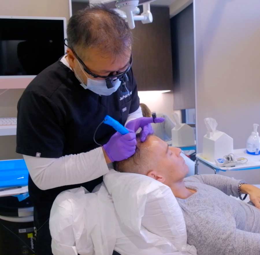 an image of Dr. Jae Pak performing a hair transplant procedure